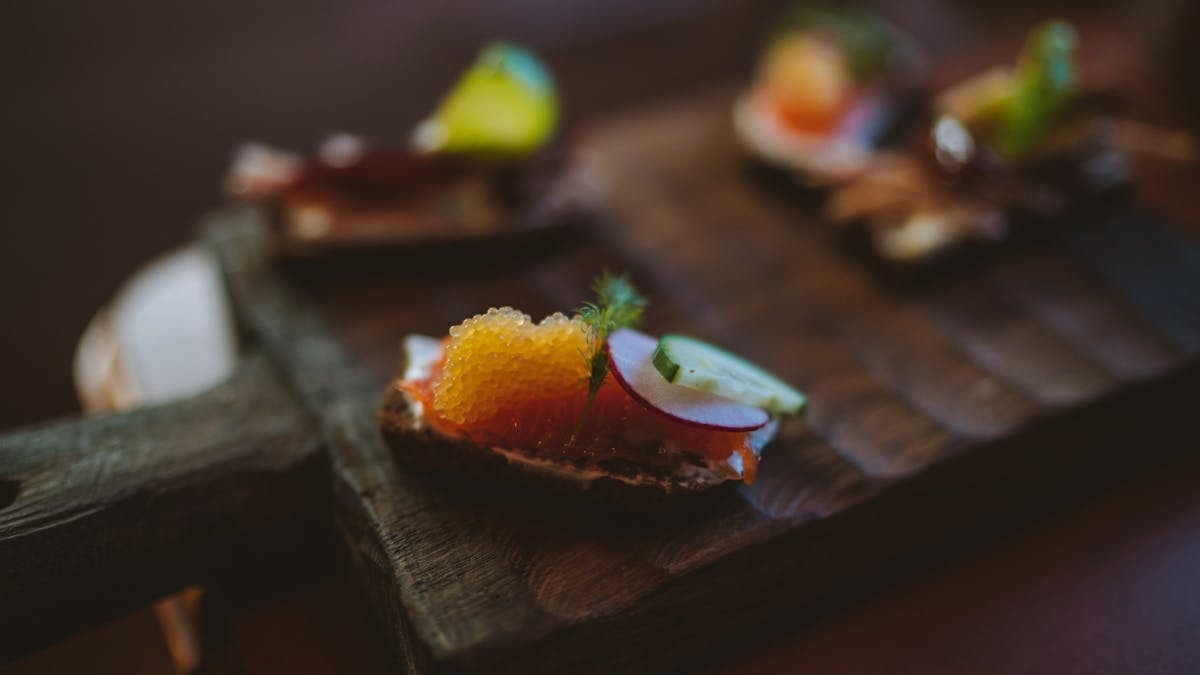 Close-up of a gourmet appetizer featuring fish roe and radish on a rustic wooden board.