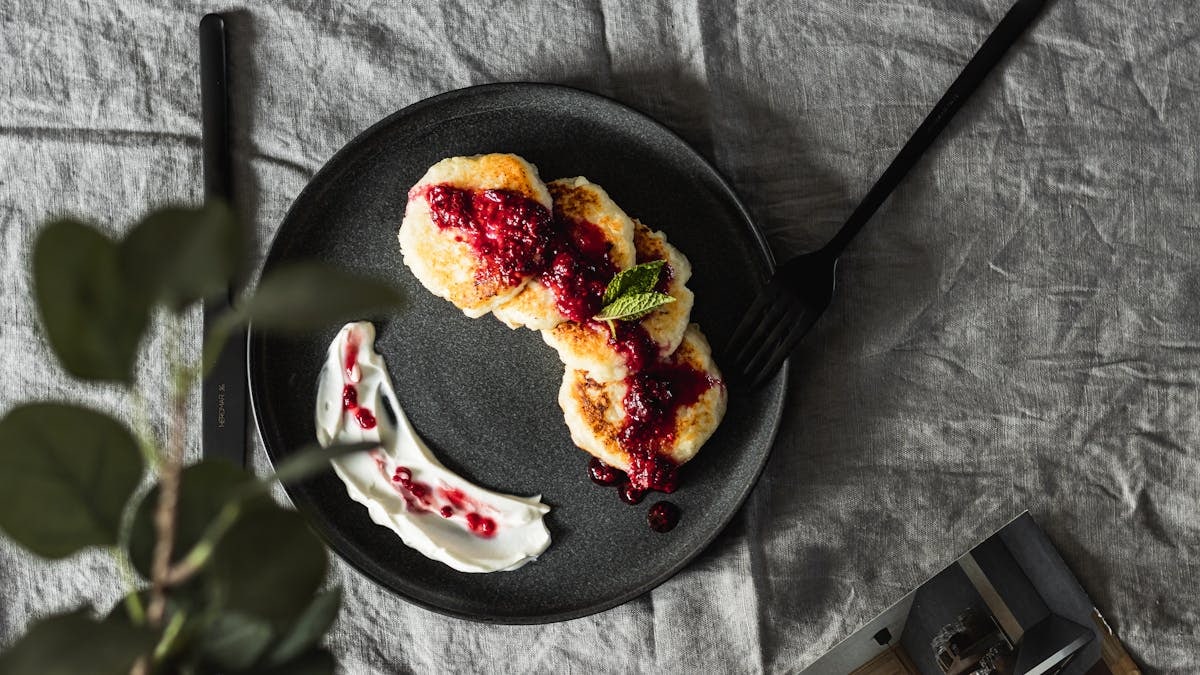 Tasty pancakes topped with fresh berry sauce on a ceramic plate, perfect for a gourmet breakfast.